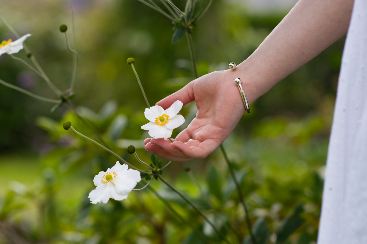 Kynance torque solid silver cuff bangle - being worn by a woman holding a white flower